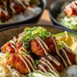 Bang bang salmon bites served over rice with shredded cabbage, cucumber, and creamy sauce