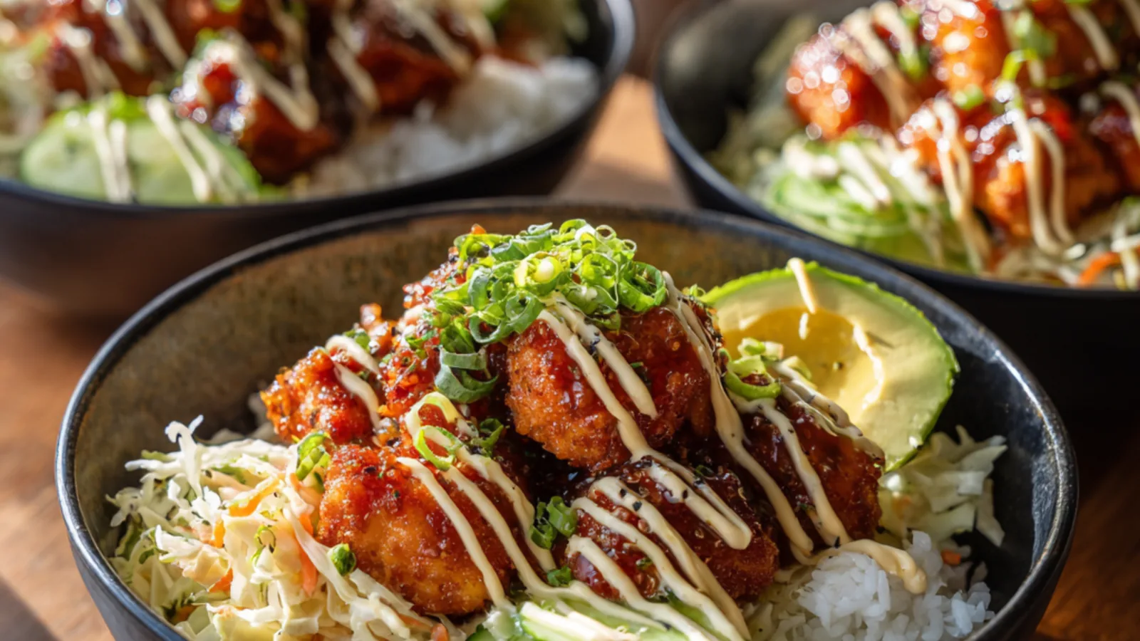Bang bang salmon bites served over rice with shredded cabbage, cucumber, and creamy sauce
