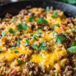 Cheesy taco rice skillet with seasoned ground beef, melted cheddar, and fresh cilantro