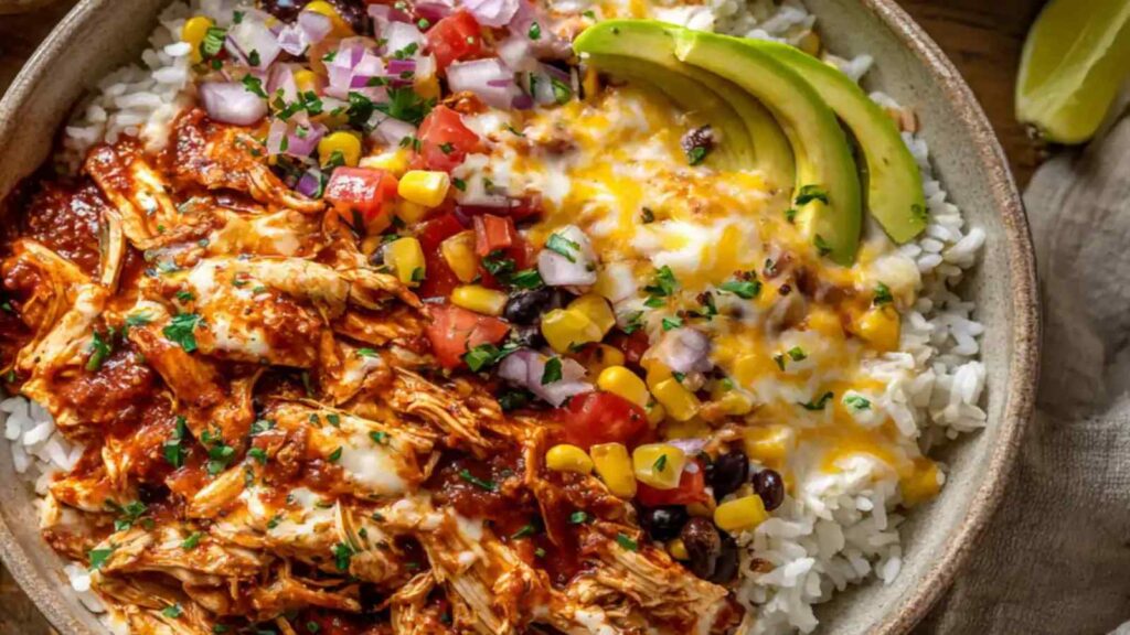 High protein chicken enchilada bowl with shredded chicken, rice, black beans, corn, melted cheese and avocado