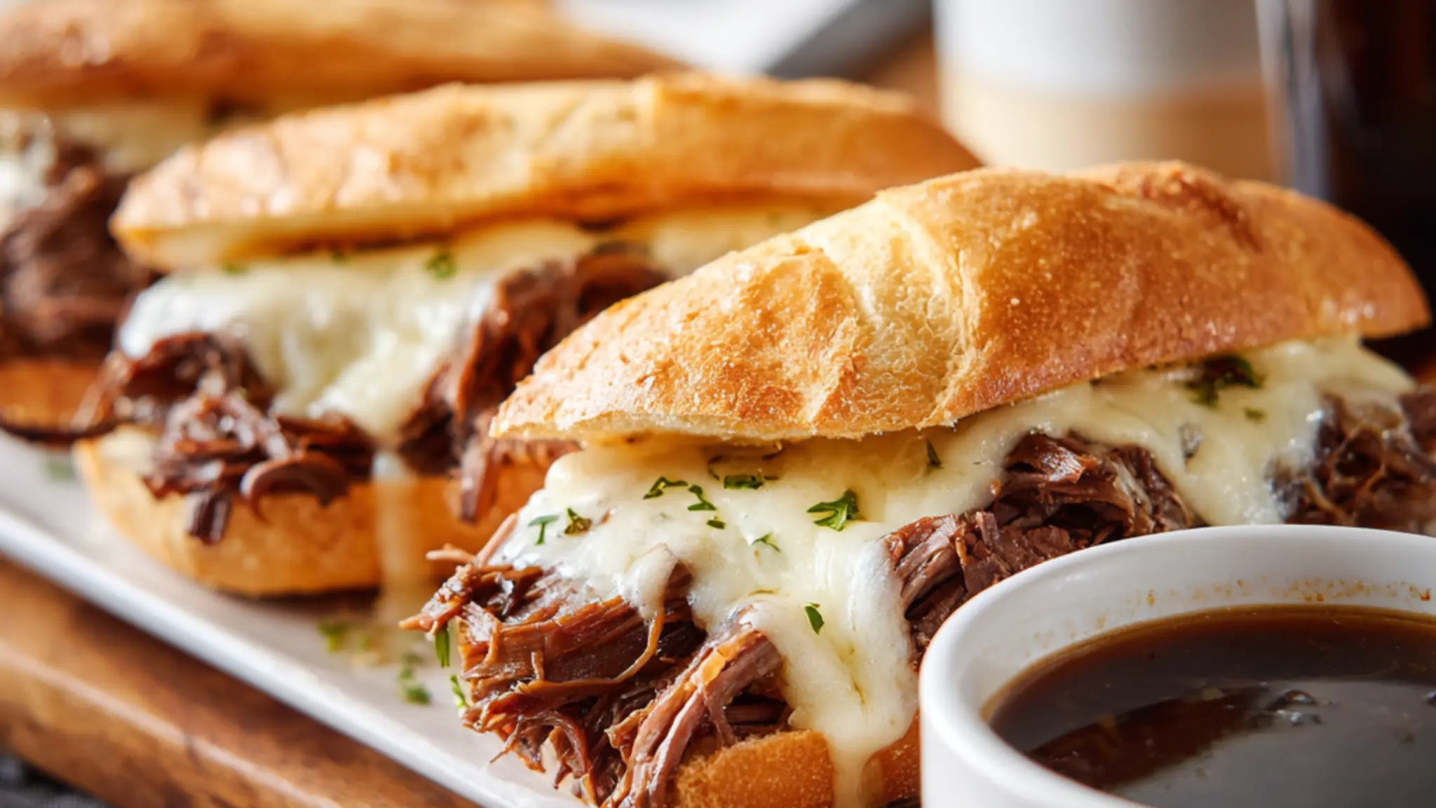 French dip sandwiches with melted cheese and shredded beef served with au jus dipping sauce
