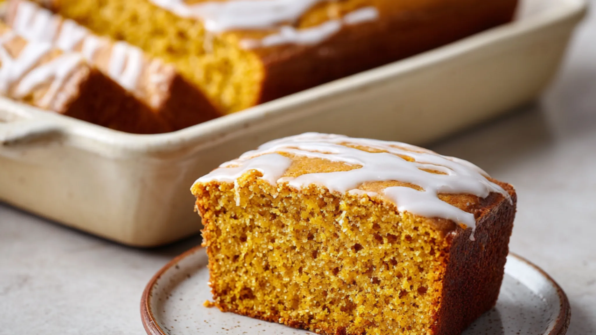 Pumpkin honey bun cake baked in a ceramic dish with a soft spiced crumb and light glaze