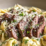 Steak slices served over cheese tortellini in a creamy garlic sauce
