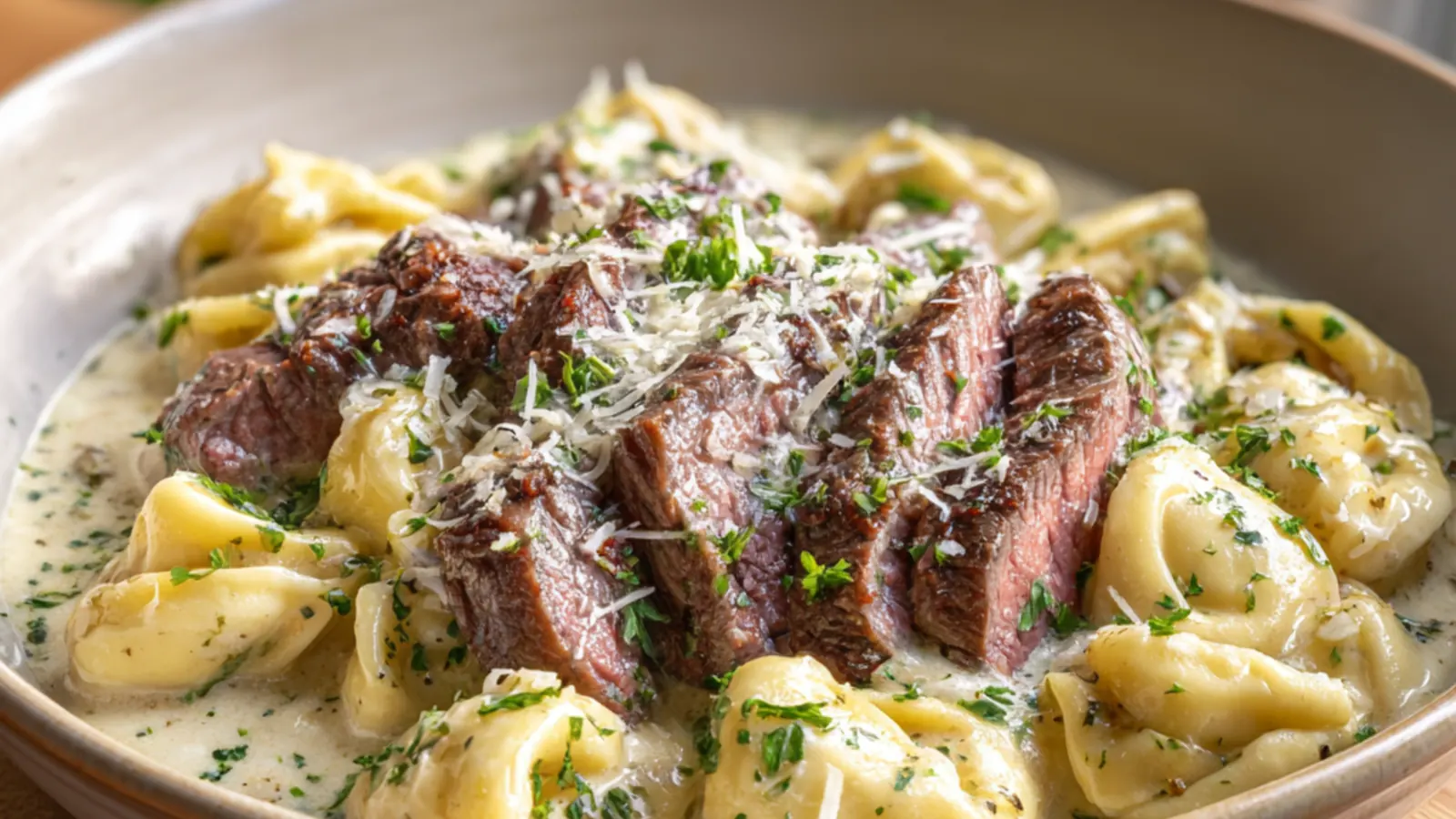 Steak slices served over cheese tortellini in a creamy garlic sauce